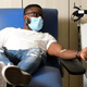Blood donor wearing mask in hospital chair with tube in arm